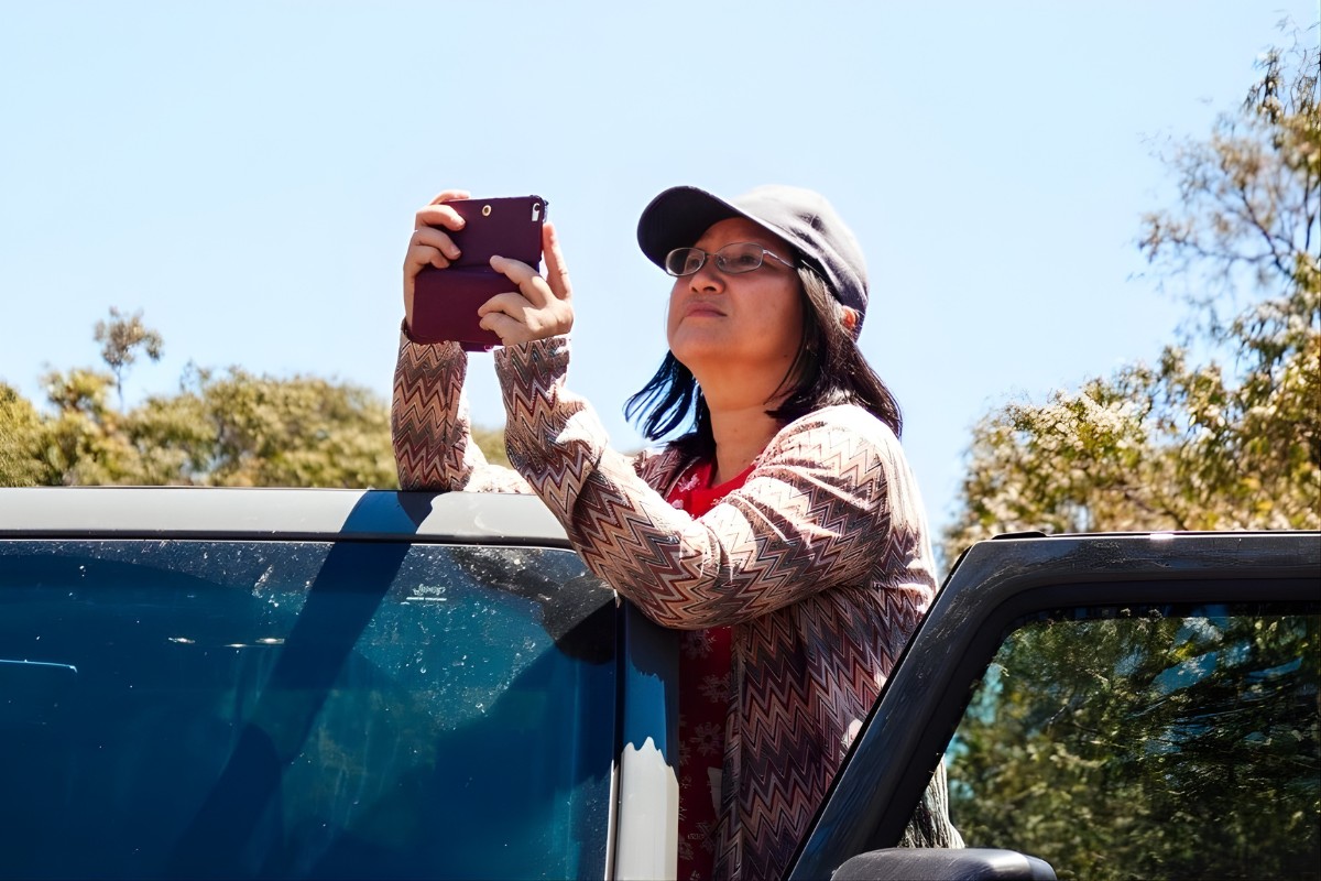 Image of woman in regional Australia looking at mobile device to check her reception