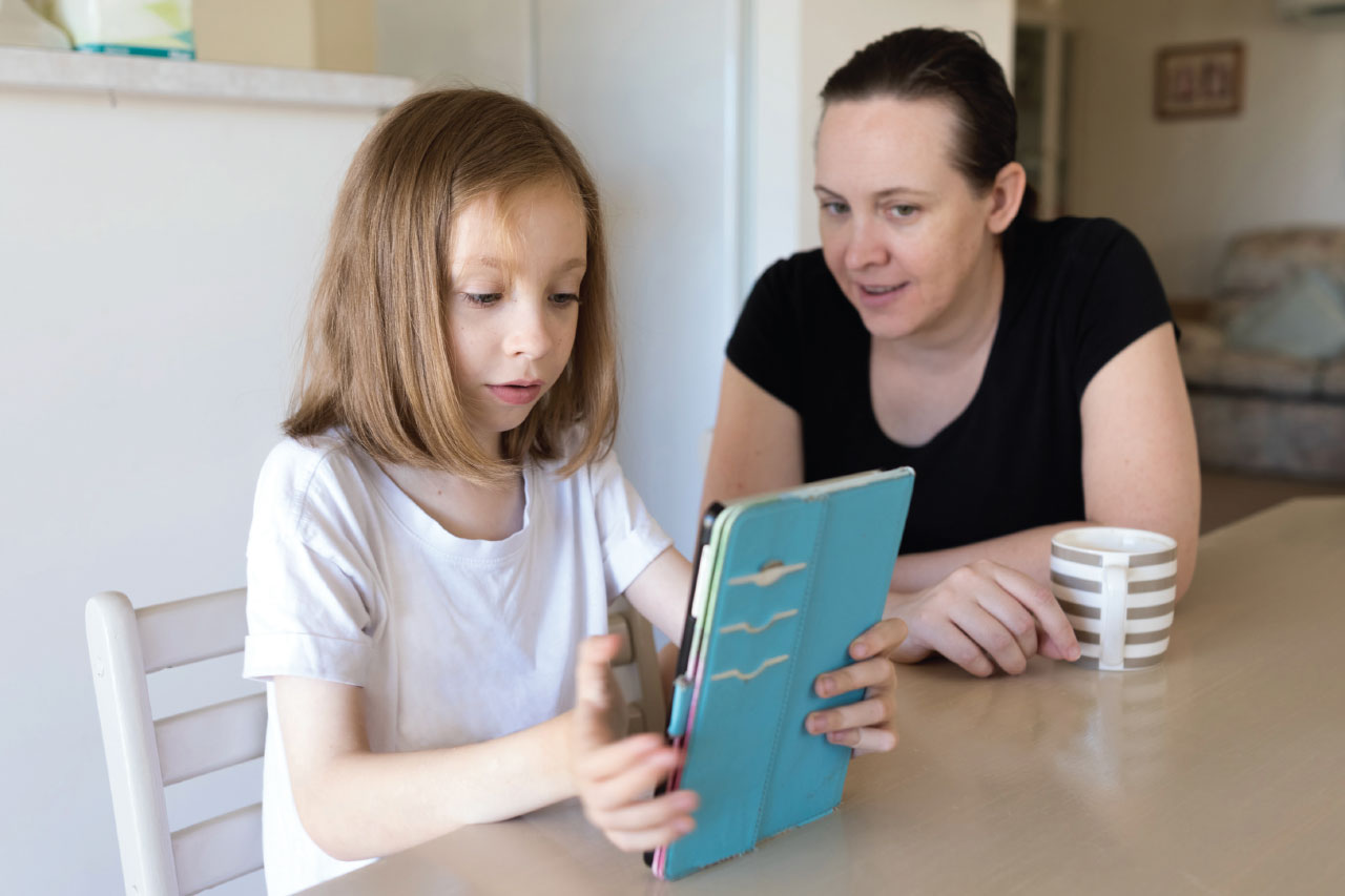 A single mother assisting her daughter using a tablet device