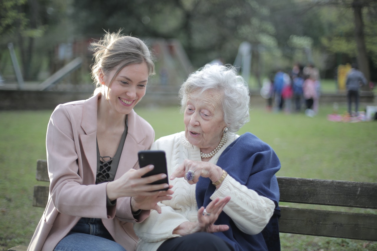 young woman showing older lady how to use a smartphone