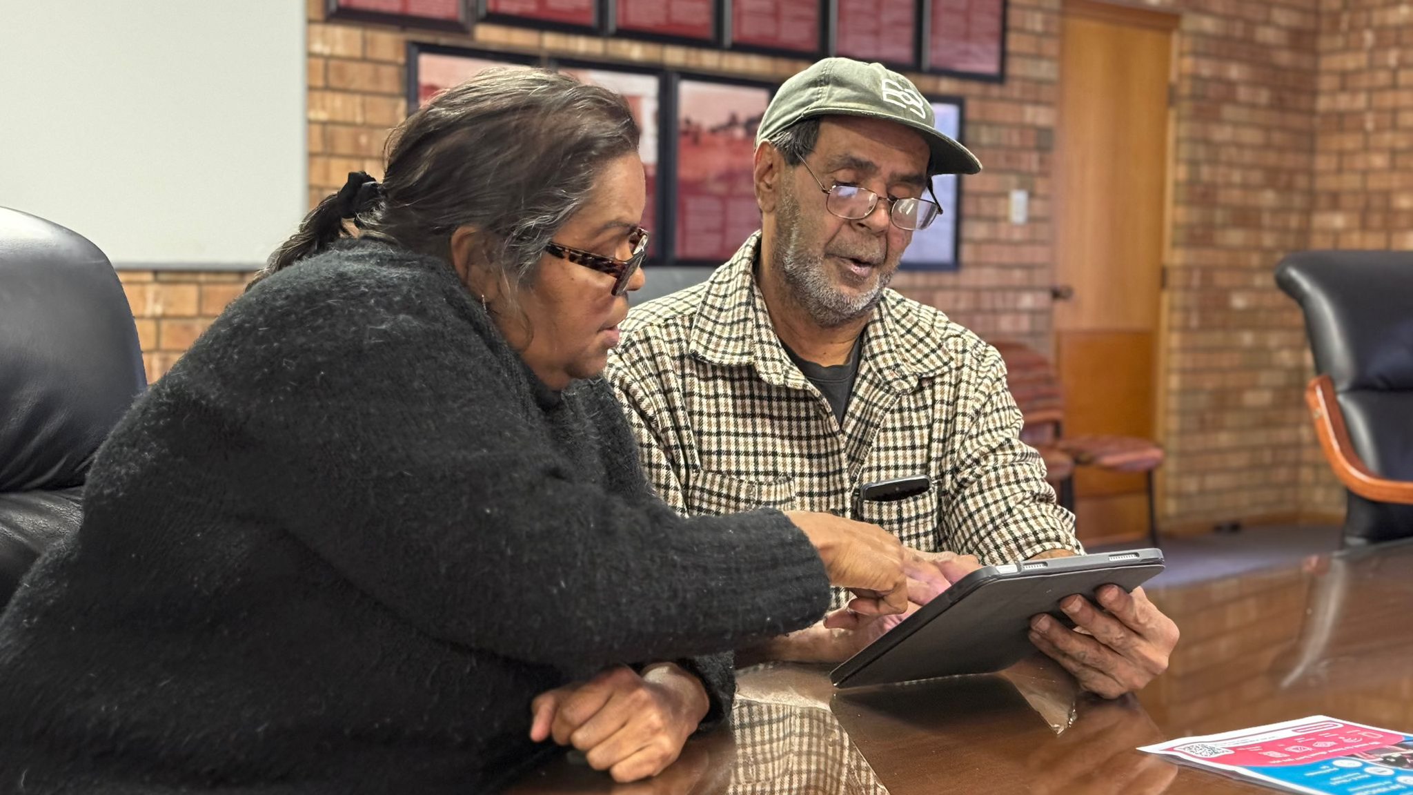 Two First Nations people looking at a tablet.